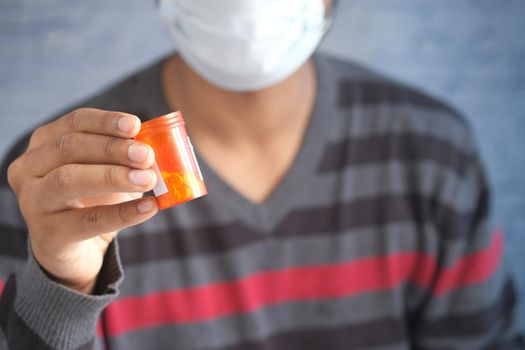young man in face mask holding medical pills ,
