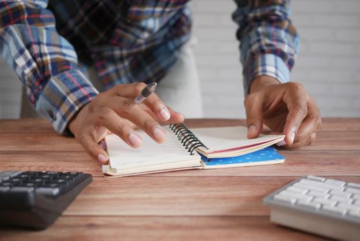 man hand writing on notepad while sited ,