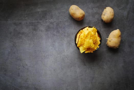 Bowl with tasty potato chips on wooden background