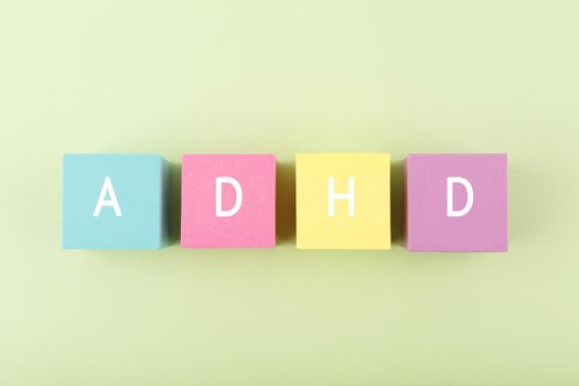 Simple minimal modern concept of Adhd. Top view of multicolored toy blocks with written Adhd letters against bright green background