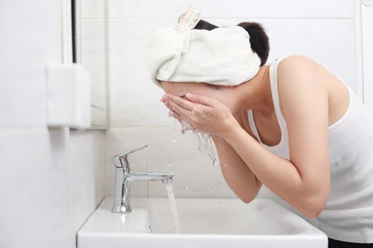 Woman happy cleanses the skin with foam on sink.