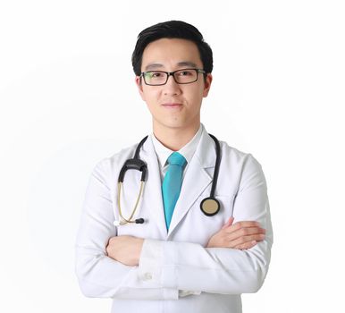 Doctor posing with arms crossed, medical staff working on blurry background.