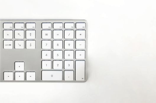 Detail of a modern white computer keyboard on a white table. Computer hardware device. Technology and internet