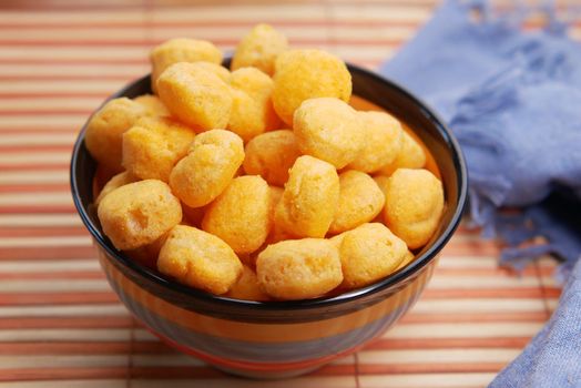 puffed corn rings chips in black bowl on white background,