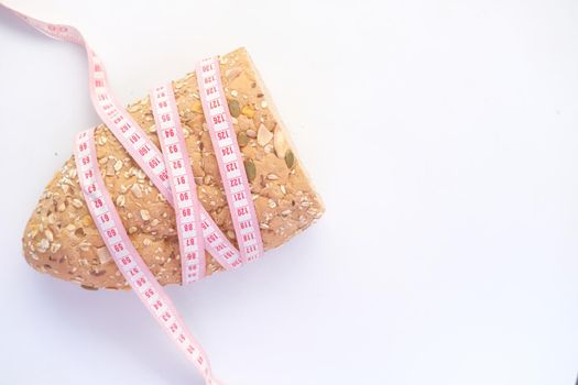 slice of whole meal bread and measurement tape on white background