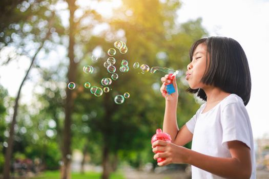 Little Asian girl blowing bubbles in the garden.