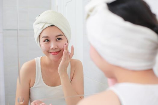Woman happy cleanses the skin with foam on sink.