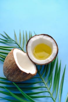 slice of fresh coconut and oil on blue background .