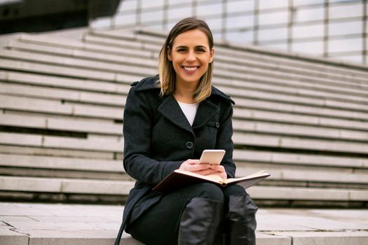 Businesswoman using mobile phone and working outdoor.