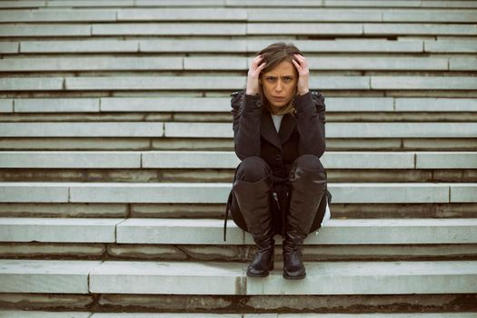 Frustrated businesswoman sitting on the staircase in the city.