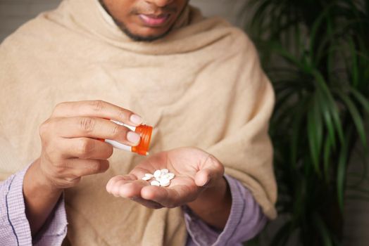 man's hand with pills spilled out of the container .