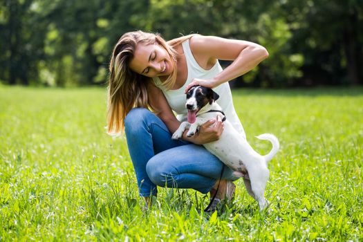 Beautiful woman enjoys spending time in the nature with her cute dog Jack Russell Terrier.