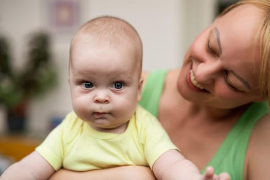 Mother enjoys holding her little cheerful baby boy.