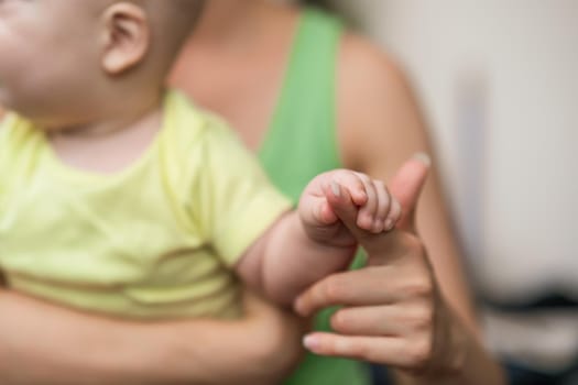 Mother  holding her baby boy, focus on their hands.