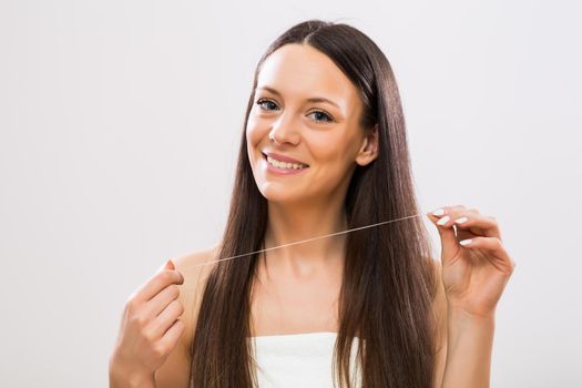 Image of beautiful brunette woman showing dental floss.