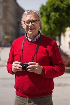 Senior man tourist enjoys photographing at the city.Image is intentionally toned.