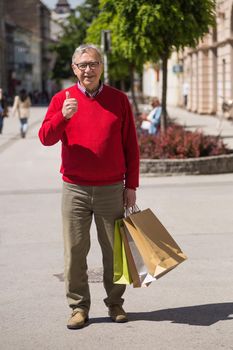 Senior man showing thumb up while enjoys in shopping at the city.