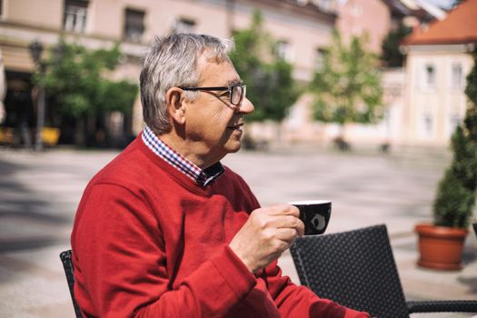 Cheerful senior man enjoys drinking coffee at the bar.Image is intentionally toned.