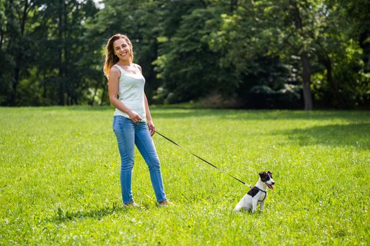 Beautiful woman enjoys walking with her cute dog Jack Russell Terrier in the nature.