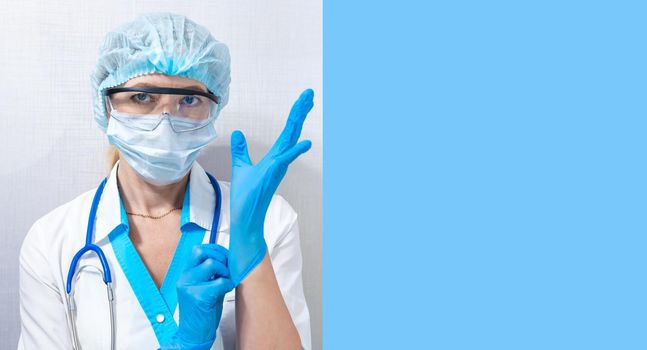 masked nurse puts on rubber blue gloves, blue background for text on the right