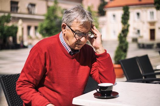 Sad senior man sitting alone at the bar.Image is intentionally toned.