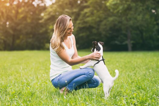 Beautiful woman enjoys spending time in the nature with her cute dog Jack Russell Terrier.Image is intentionally toned.