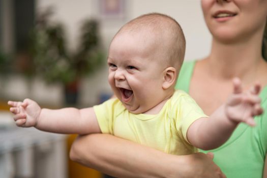 Mother enjoys holding her little cheerful baby boy.