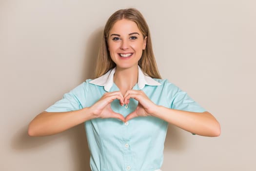Portrait of medical nurse showing heart shape with hands.