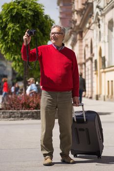 Senior man tourist enjoys photographing at the city.Image is intentionally toned.