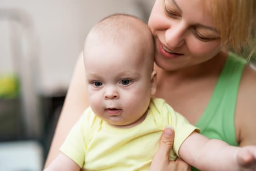 Mother enjoys holding her little cheerful baby boy.