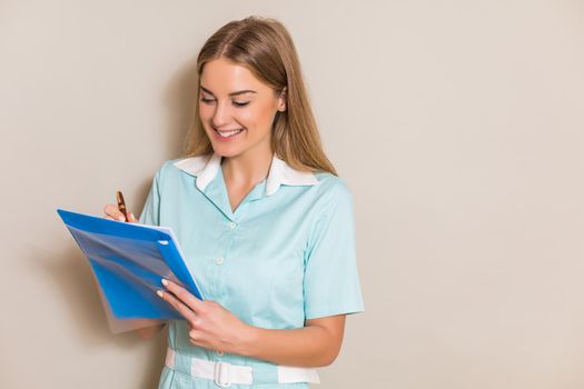 Portrait of beautiful nurse writing notes.