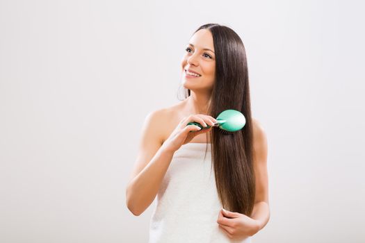Cheerful woman brushing her beautiful long hair.