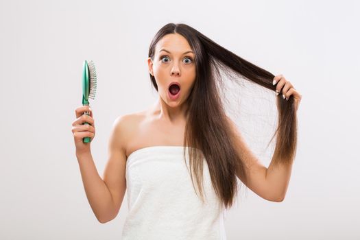 Beautiful woman in panic because of hair loss looking at camera.