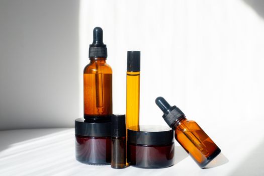 Cosmetic jars with oils on a white background . Light and shadows. Minimalism. Copy space. Cosmetology. Skin care. Cosmetic bottles. spa treatments