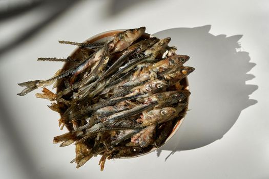 Fish heads and bones left after eating on a plate. Fried fish skillet on a light background. Fish skeletons