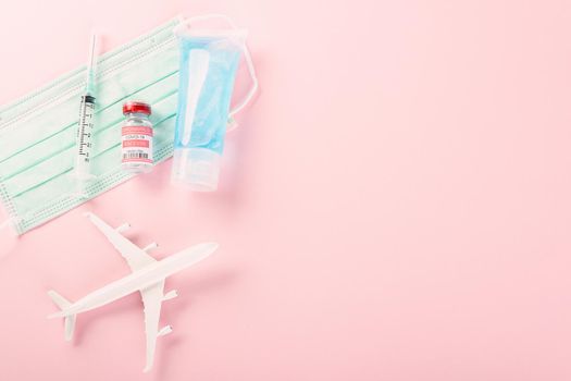 Model plane, COVID-19 coronavirus vaccine vials bottles for vaccination and medical face mask, buy vaccine, tourism worldwide delivery studio shot isolated pink background with copy space for text