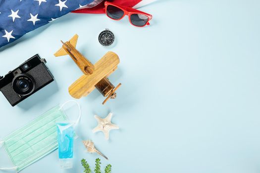 World Tourism Day during coronavirus pandemic, model plane with face mask and American flag, STOP and safe travel, studio shot isolated blue background with copy space, holiday trip vacation concept