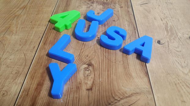 Plastic colored alphabets making words 4 july USA are placed on a wooden floor. These plastic letters can be used for teaching kids.