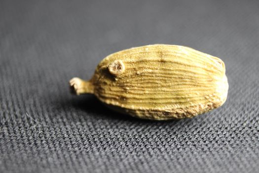 Closeup top view of dried green Elettaria cardamomum fruits with seeds, cardamom spice scattered on white background