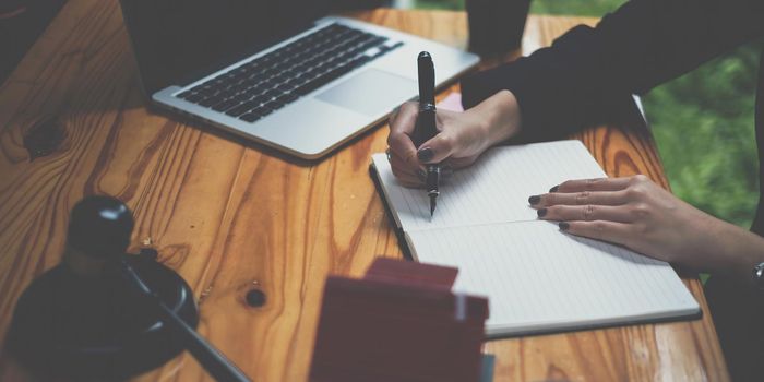 Business woman or legal advisor writting in book on wooden desk in office. Law, legal services, advice,Judge auction and real estate concept