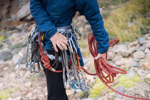 A young girl is mountaineering, checking equipment and straightening the rope before going in a bunch to the top of the mountain.