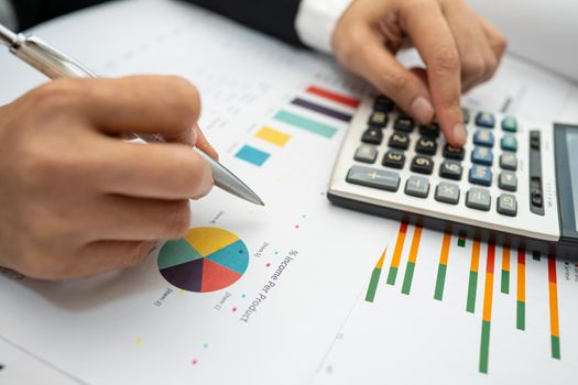 Asian accountant working and analyzing financial reports project accounting with chart graph and calculator in modern office, finance and business concept.