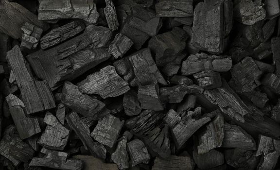 Close up background texture of many black lump charcoal pieces ready for barbecue grill, elevated top view, directly above