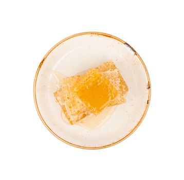 Close up stack of several fresh cut golden comb honey slices on plate isolated on white background, elevated top view, directly above