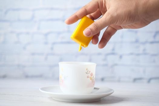 young women putting artificial sweetener in tea