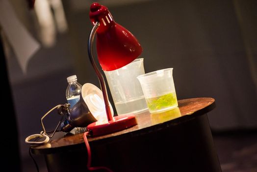 A close up product photo of science experiment materials including colorful green liquid filled cup.
