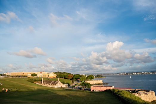 Cityscape of Old San Juan at sunset with views of blue sky and historic buildings. and homes by the water.