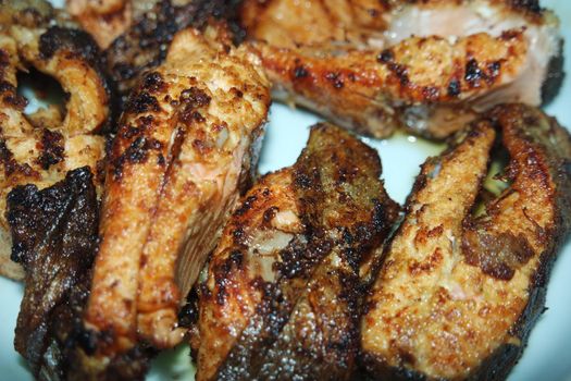 Spicy and crunchy barbecue of fried fish fillet on a white background. Homemade grilled trout fish steaks for health nourishments.