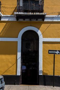 Geometric composition of a yellow building with white arch along a street in San Juan, Puerto Rico.