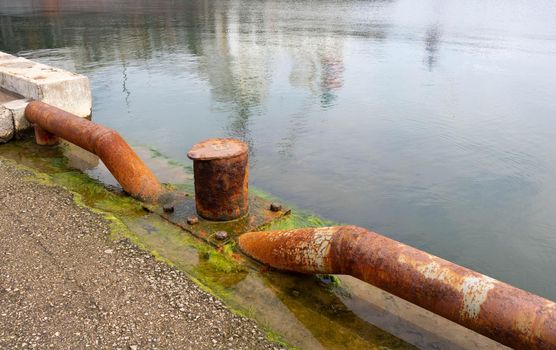 Mooring bollard for boats with a rusty texture on the sea pier.